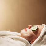lady relaxing with face mask, cucumber and white robe and towel