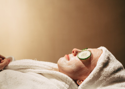 lady relaxing with face mask, cucumber and white robe and towel