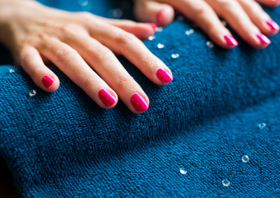 ladies pink nails resting on blue towel after manicure